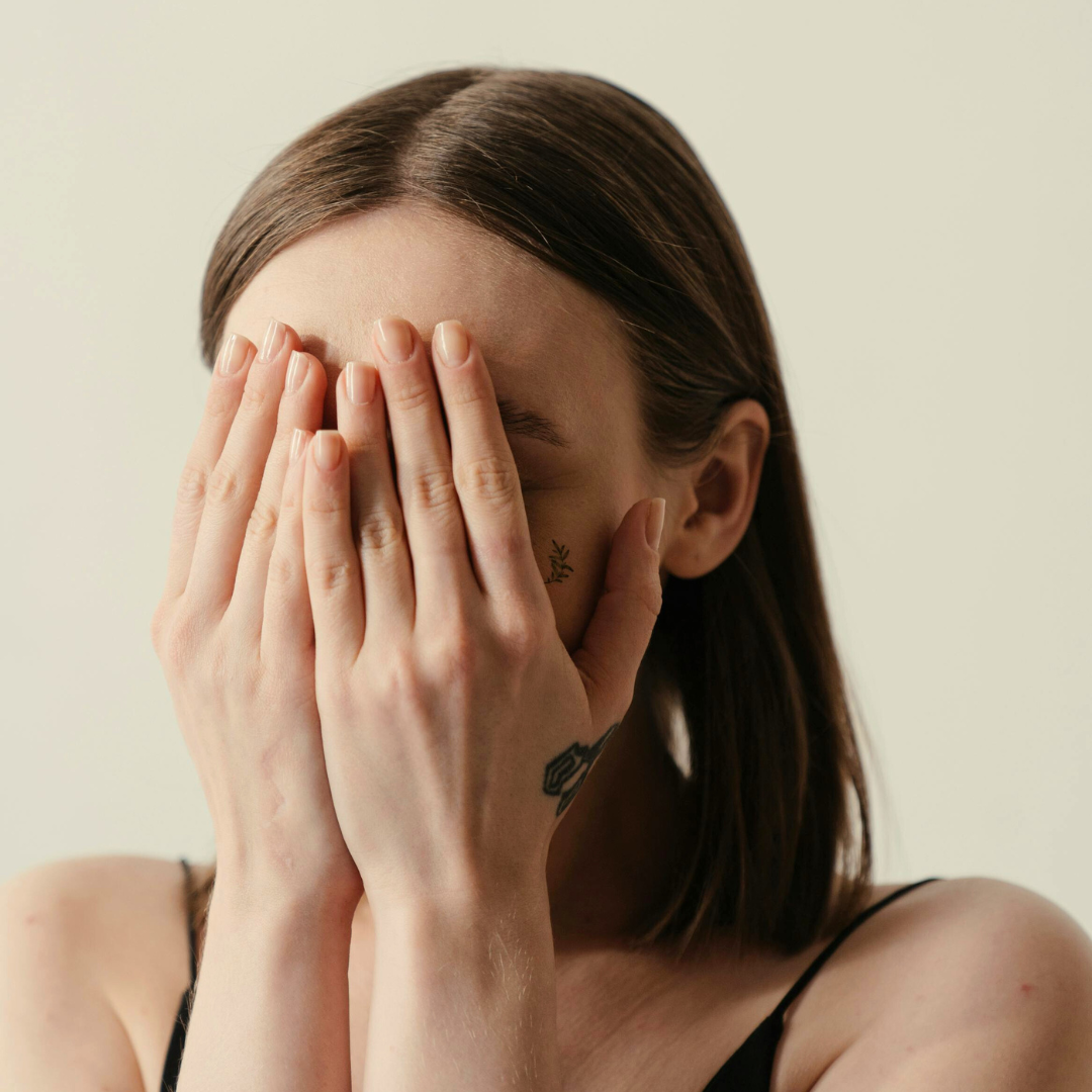 woman with hormonal acne covering her face